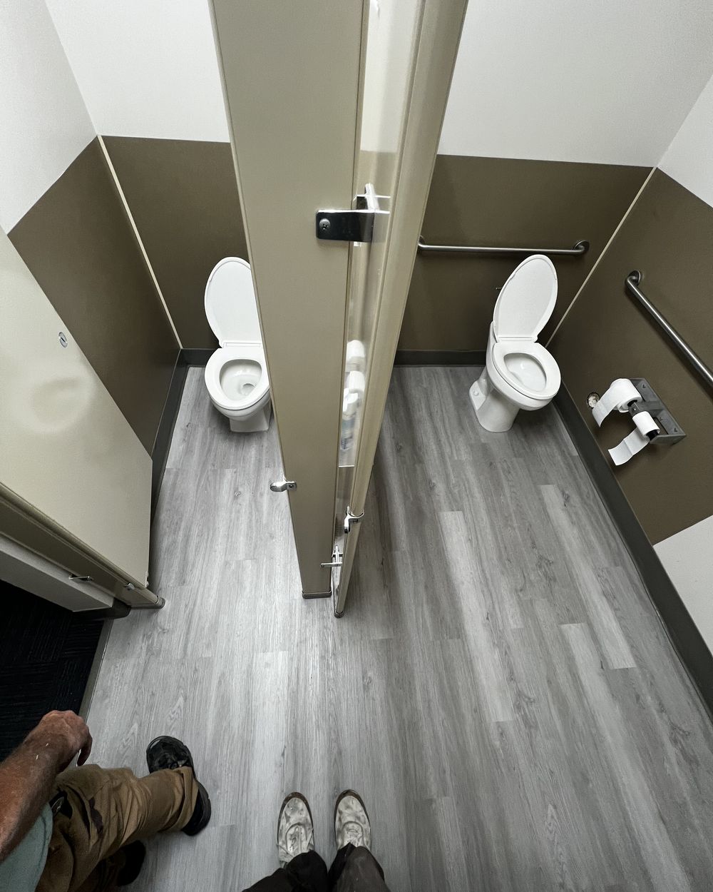 The same restroom with a new grey plank floor run through both stalls.
