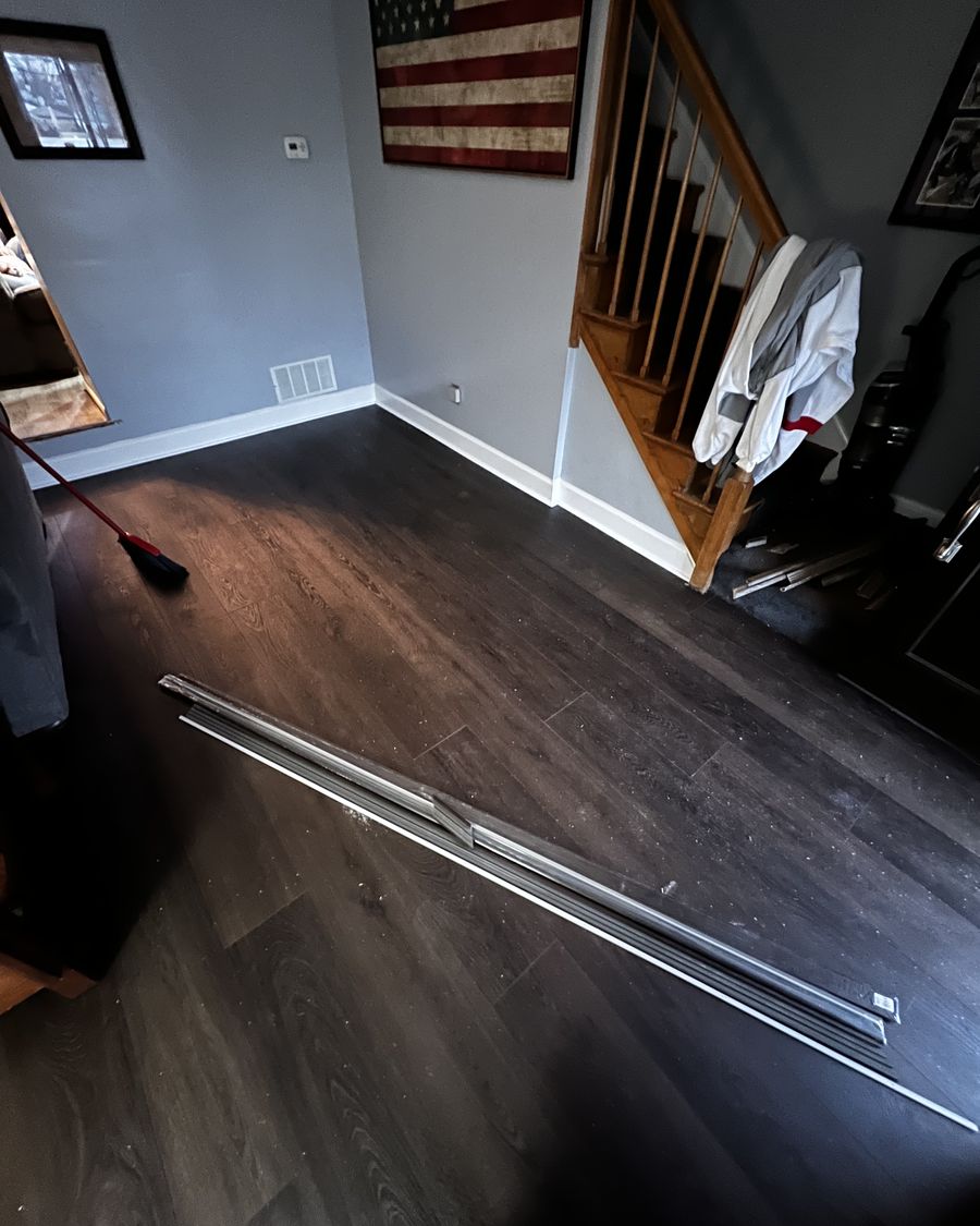 Dark plank flooring against white baseboard in a living room.