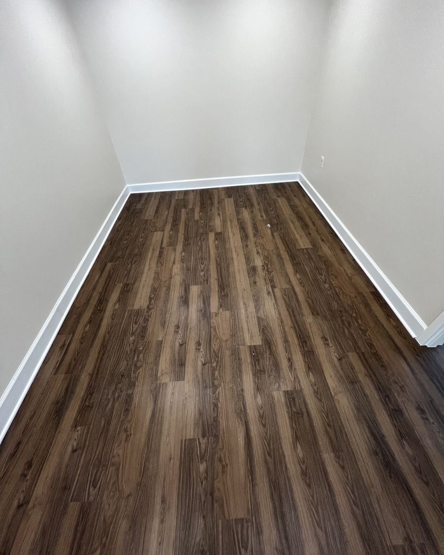 Plank flooring meeting crisp white baseboard in a finished corner.