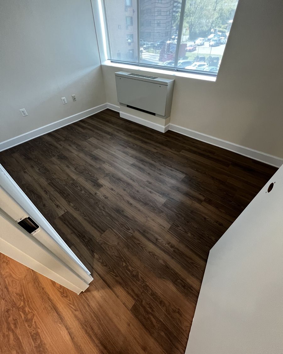 A finished living area with new plank flooring and baseboard.